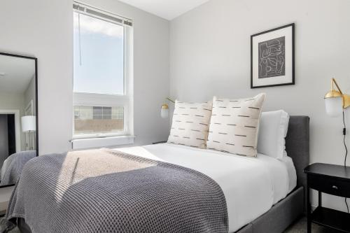 a white bedroom with a large bed with white pillows at Blueground Brighton gym pool wd doorman BOS-1031 in Boston