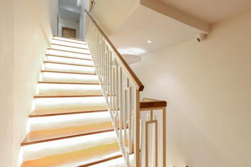 a staircase in a house with white walls and wooden railings at Casabella Homestay Batam in Nagoya
