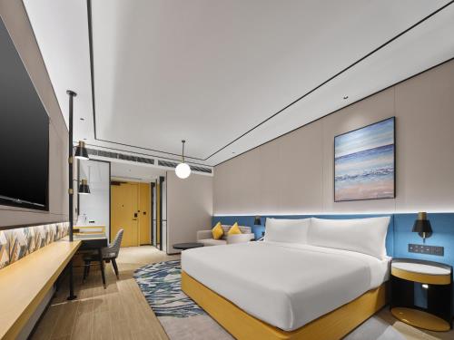 a hotel room with a bed and a tv at Hilton Garden Inn Kunming Dianchi in Kunming