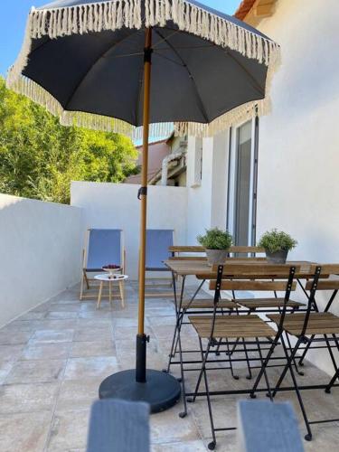 - une table et des chaises sous un parasol sur la terrasse dans l'établissement Villa Maya - 3 Groussan - Avignon - CLIM - TERRASSE, à Avignon