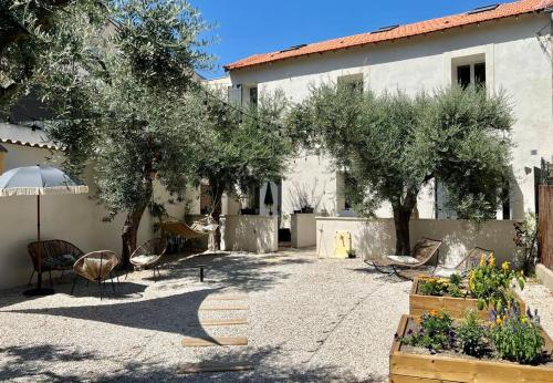 une cour avec des chaises et des arbres ainsi qu'un bâtiment dans l'établissement Villa Maya - 3 Groussan - Avignon - CLIM - TERRASSE, à Avignon