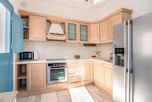 a kitchen with wooden cabinets and a refrigerator at Lunar Villa in Glastros