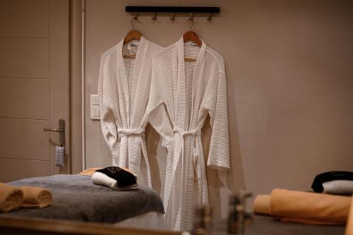 a white robe hanging on a wall in a bathroom at Restia in Almiros Beach