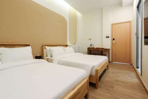 two beds in a room with white sheets at Casabella Homestay Batam in Nagoya