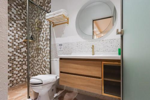 a bathroom with a toilet and a sink and a mirror at Casabella Homestay Batam in Nagoya
