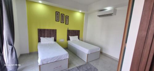 a room with two beds and a green wall at Happy Living in Noida