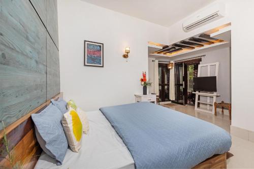 - une chambre avec un lit bleu et une télévision dans l'établissement Amaltas with Pvt Pool & Lawn By StayVista, à Rāmnagar