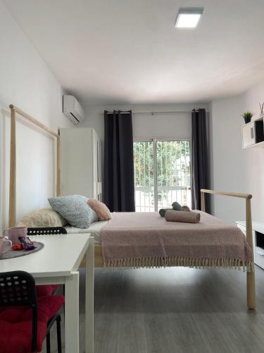 a bedroom with a bed and a table and a window at joan miro in Torremolinos