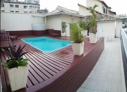 a deck with potted plants and a swimming pool at Pousada Aquários in Cabo Frio