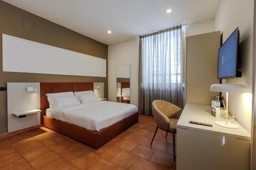 Schlafzimmer mit einem Bett und einem Schreibtisch mit einem TV in der Unterkunft Palazzo della Città in Agnone