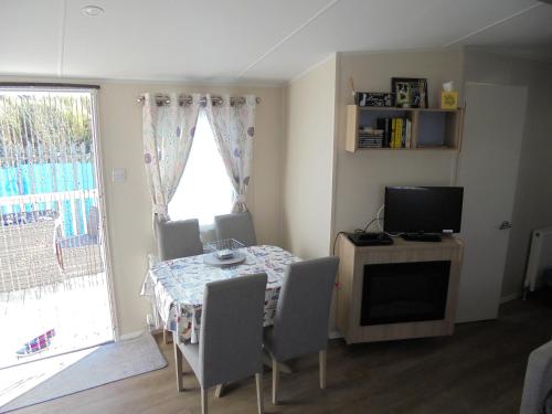 a dining room with a table with chairs and a television at Seaview Ingoldmells Linwood II 10 Berth, 4 Bedrooms, Central heated in Ingoldmells
