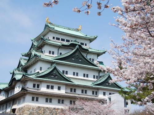 a japanese castle withakura trees in front of it at Prince Smart Inn Nagoya Sakae in Nagoya