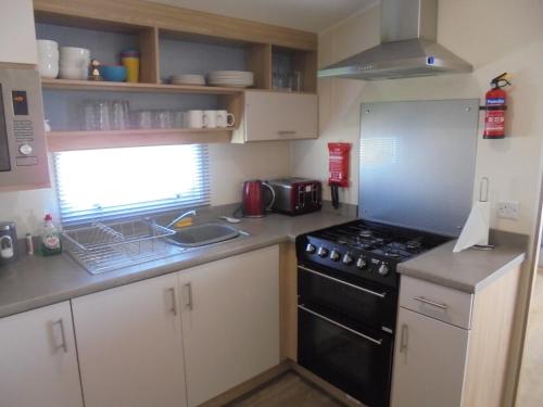 a small kitchen with a stove and a sink at Seaview Ingoldmells Linwood II 10 Berth, 4 Bedrooms, Central heated in Ingoldmells