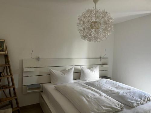 ein Schlafzimmer mit einem großen weißen Bett und einem Kronleuchter in der Unterkunft Ferienwohnung an der Elbe in Dresden