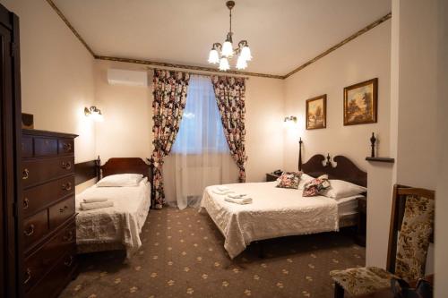 a bedroom with two beds and a dresser and a window at Hotel Trylogia in Zielonka