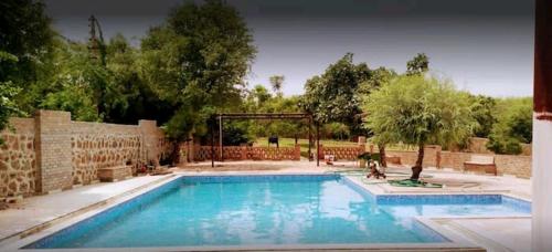 a swimming pool in a yard with a brick wall at Whispering farm in Gurgaon