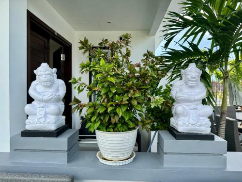 two white statues sitting on a table with plants at Villa Rumah Putih Abu Abu in Senggigi 