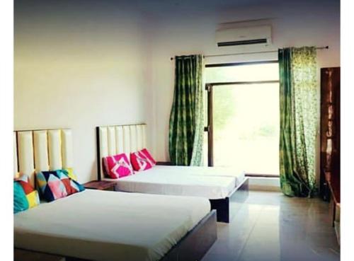 a room with two beds and a window with curtains at Whispering farm in Gurgaon
