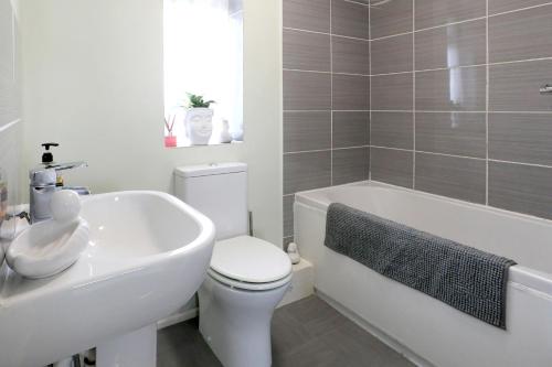 a bathroom with a toilet and a tub and a sink at Lovely 3 bedroom house with free parking & garden in Norwich