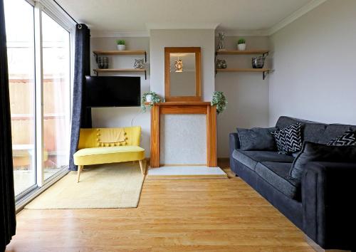 a living room with a couch and a yellow chair at Lovely 3 bedroom house with free parking & garden in Norwich