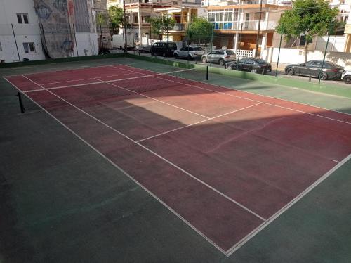 una pista de tenis en un aparcamiento con coches en Apartamentos Bonaire 1ª Linea Wifi Solo Familias Serviplaya, en Gandía