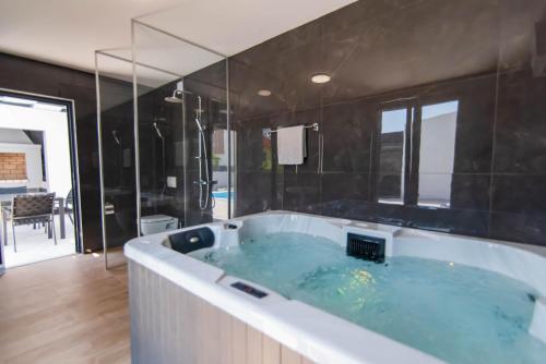 uma grande banheira numa casa de banho com azulejos pretos em Villa Neva ZadarVillas em Ražanac