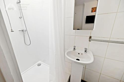 a white bathroom with a sink and a shower at Cosy Tottenham Apartment Sleeps 4 in London