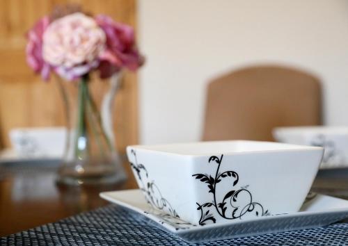 a bowl on a table with a vase of flowers at Lovely 3 bedroom house with free parking & garden in Norwich