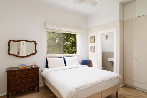 1 dormitorio con cama, espejo y ventana en Exquisite Home on Rothschild Bld by FeelHome, en Tel Aviv