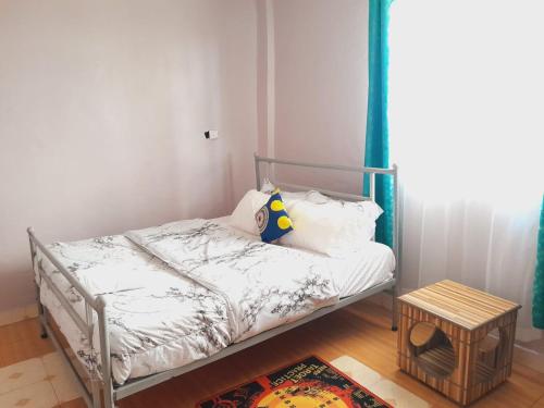 um pequeno quarto com uma cama e uma mesa em Hotfoot Homestays em Isiolo