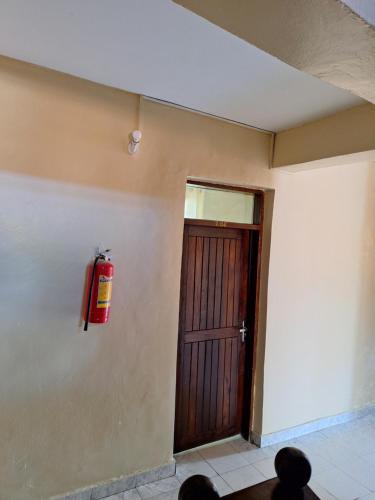 un extintor de incendios en la pared junto a una puerta en King Palace Hotel, en Dar es Salaam