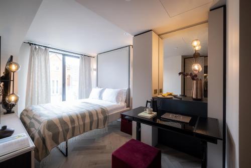 a bedroom with a bed and a desk with a mirror at The Brondesbury by Nestor in London