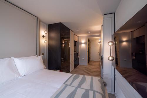 a bedroom with a large white bed and a hallway at The Brondesbury by Nestor in London