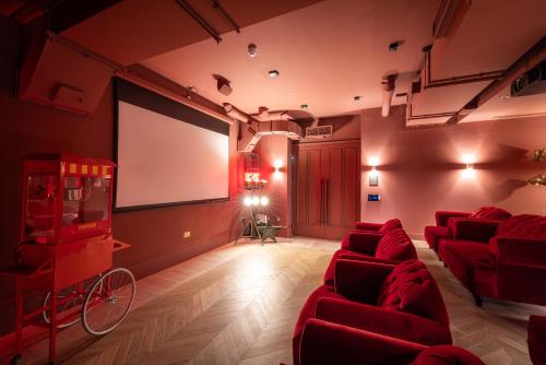 einen Filmraum mit roten Stühlen und einem Bildschirm in der Unterkunft The Brondesbury by Nestor in London