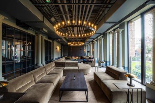 un grand salon avec des canapés et un lustre dans l'établissement The Brondesbury by Nestor, à Londres