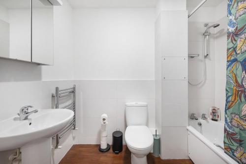 a white bathroom with a toilet and a sink at Deluxe Shoreditch flat next to station with views in London