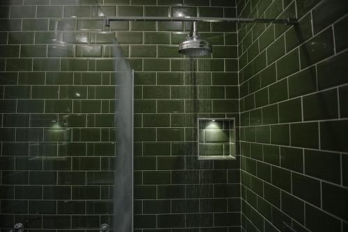 een douche met een groene betegelde muur met licht bij Shortflatt Tower in Longwitton