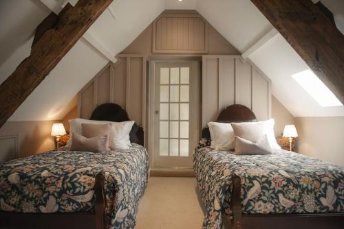 a attic bedroom with two beds and two lamps at Shortflatt Tower in Longwitton