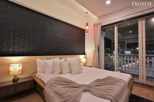 a bedroom with a white bed with a brick wall at EKOSTAY Gold - Amara Villa in Alibaug