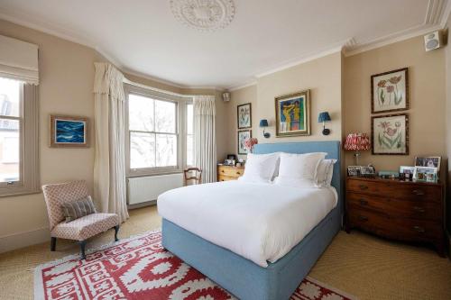 a large bedroom with a blue bed and a chair at Veeve - Riverside Serenade in London