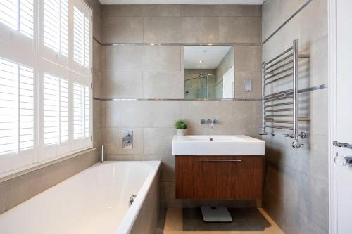 a bathroom with a tub and a sink and a mirror at Veeve - Riverside Serenade in London
