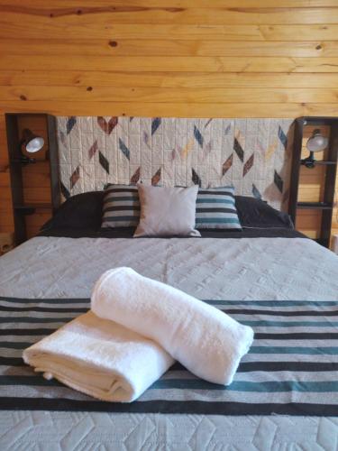 a bed with two towels on top of it at D'Charrúas Cabañas Chajarí in Chajarí
