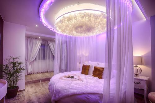 - une chambre avec un grand lit et un éclairage violet dans l'établissement Le Clos des Thermes Suites de Luxe avec wellness privatif, à Chaudfontaine