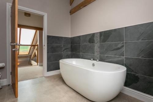 a bathroom with a white bath tub in a room at Brockram Barn in Kirkby Stephen