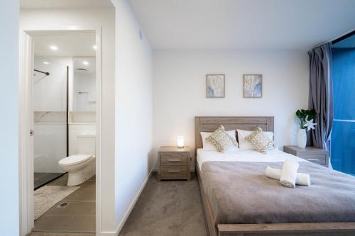 a bedroom with a bed and a bathroom at Urban Elegance 2B2B w parking, pool South Brisbane in Brisbane
