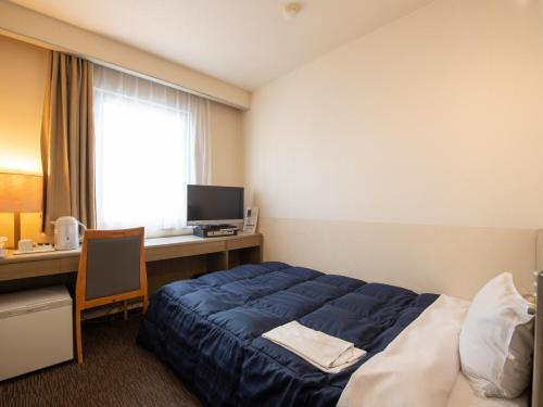 a bedroom with a bed and a desk with a computer at Hotel Iidaya in Matsumoto