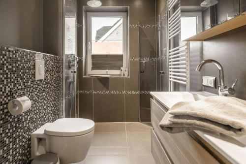 a bathroom with a toilet and a sink and a window at Baltic House Sandburg in Timmendorfer Strand