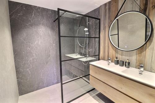 W łazience znajduje się umywalka i lustro. w obiekcie Le cosy Cottage du chêne w mieście Lasne