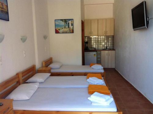 una camera con tre letti e una cucina di Lydia Mare ad Agios Kirykos