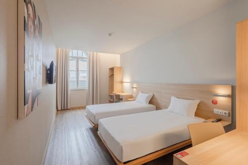 a hotel room with two beds and a desk at Moov Hotel Porto Centro in Porto